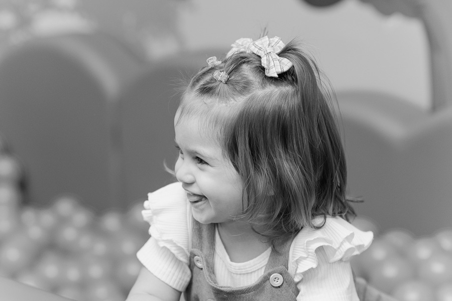 O sorriso que ilumina tudo! Um close que revela a felicidade genuína da Liz enquanto brincava. Como fotógrafo de aniversário infantil, busco os detalhes que contam a história emocional da festa.