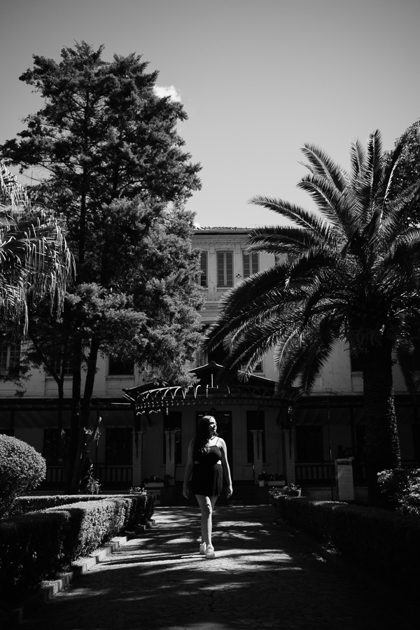 Fotografia artística P&B: O olhar marcante da debutante emoldurado pelas folhas. Criatividade em ensaios de 15 anos em SJC.