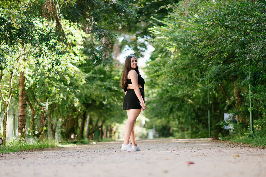 Composição e profundidade: A debutante na alameda principal do parque. Fotografia de arquitetura e pessoas em harmonia em SJC.