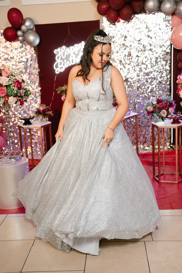Vestido de 15 anos prateado: Foto de corpo inteiro destacando o caimento e o brilho do modelo escolhido.