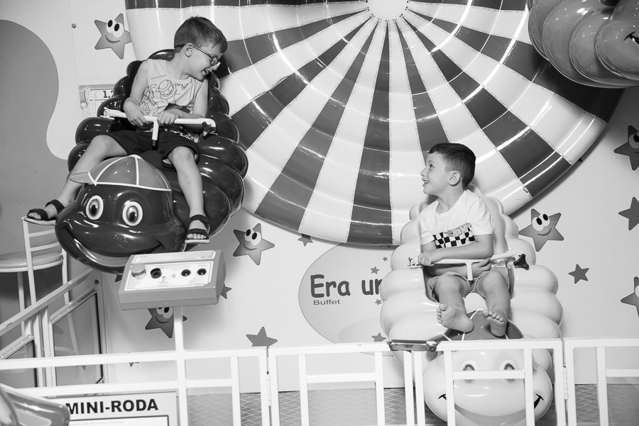 Piloto em ação! O preto e branco para destacar a concentração e a alegria do João no comando do seu carro. Uma imagem cheia de estilo para uma festa temática de corrida.