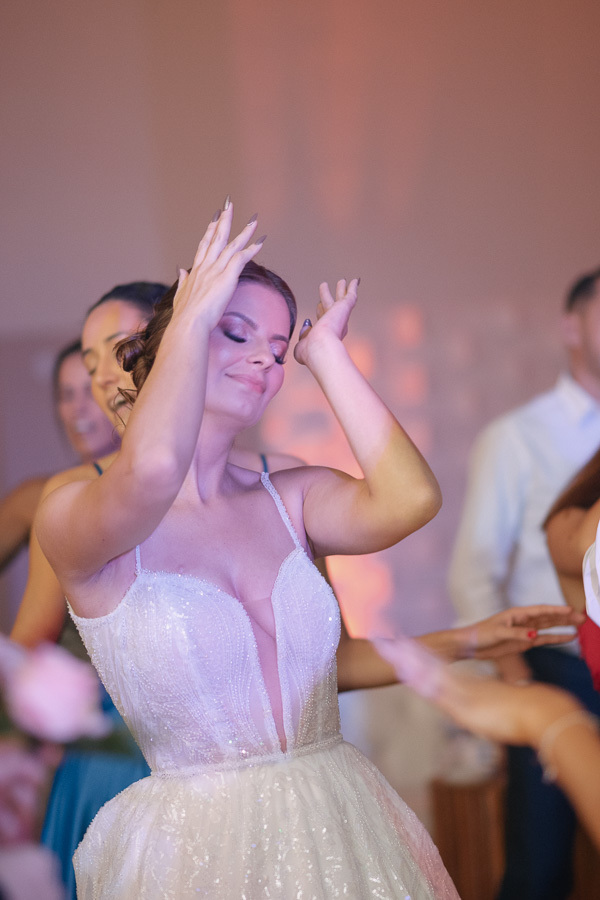 Noiva Isabelle dançando de olhos fechados, sentindo a música e a energia da festa. Momento de pura liberdade na pista de dança, transmitindo a alegria de celebrar o casamento. Fotografia espontânea que captura a emoção do momento.