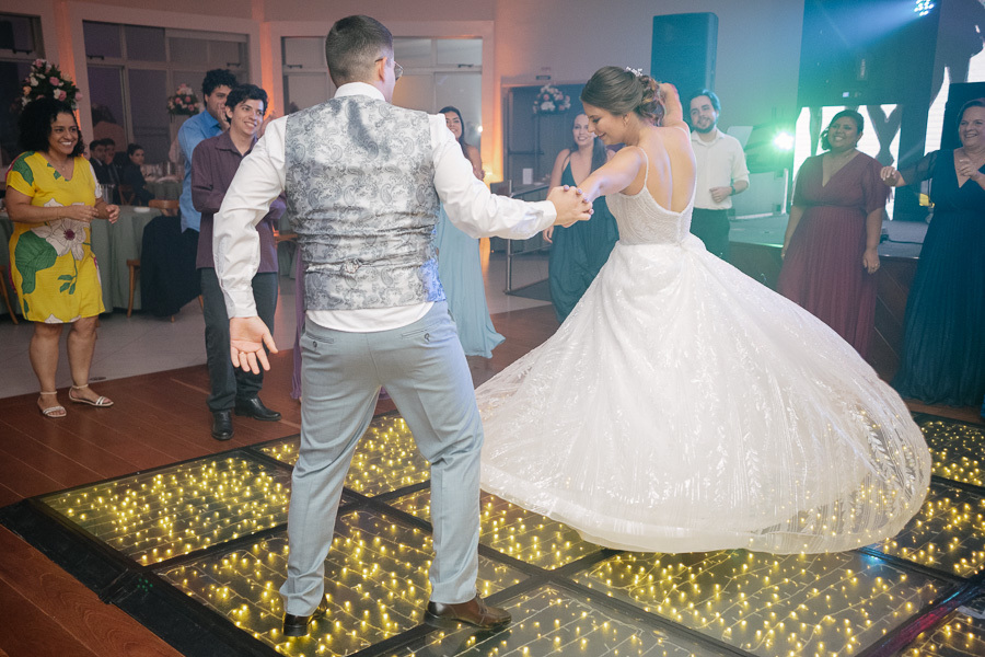egistro do movimento e da leveza da dança dos noivos na pista de LED iluminada. Isabelle sorri enquanto gira, celebrando a noite inesquecível de seu casamento ao lado de Marcus e seus convidados.