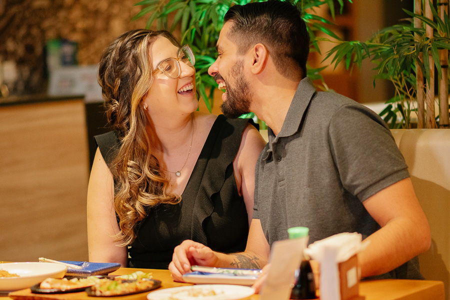 Sorrisos espontâneos de Juliano e Tainara no Hioki Sushi em São José dos Campos. Ensaio pré-wedding lifestyle em SJC. Fotógrafo de casamento no Vale do Paraíba registrando momentos reais e divertidos de casal. Inspire-se com esse pré-casamento urbano!