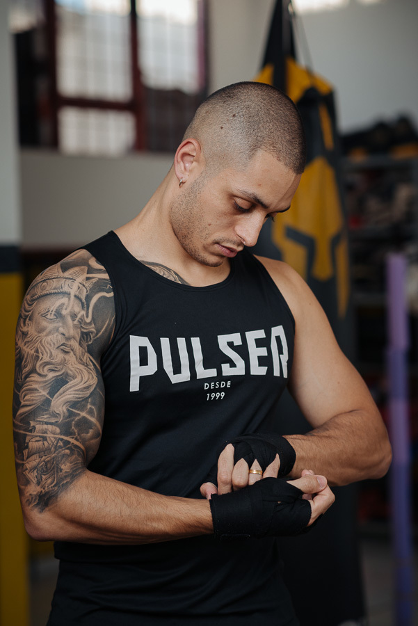 Luidgi se prepara para o kickboxing no ensaio pré-casamento com Aline. Fotografia profissional de noivado com temática esportiva e lifestyle na academia. Registre sua essência com um ensaio de casal autêntico e criativo. Fotos de casamento com estilo.