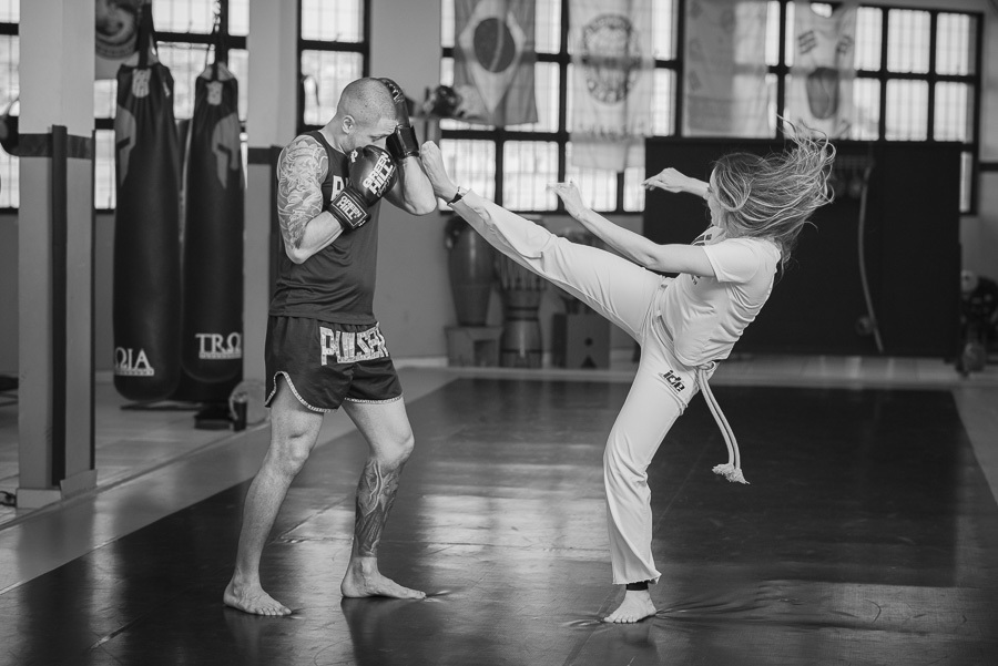 Ação e emoção no ensaio pré-casamento de Luidgi e Aline: o encontro da capoeira com o kickboxing. Fotografia de casal em preto e branco, capturando a energia do esporte e a sintonia do noivado. Garanta um registro profissional e criativo.