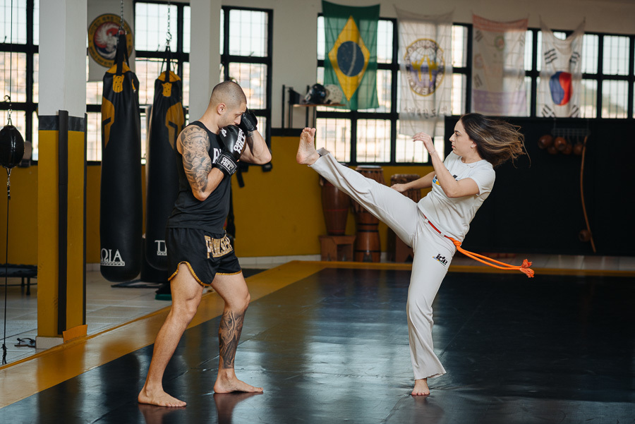 Sintonia e ação no ensaio pré-casamento na academia. O encontro da capoeira e kickboxing em fotos de noivado vibrantes. Fotografia profissional para casais que desejam um álbum de casamento que conte sua história real.