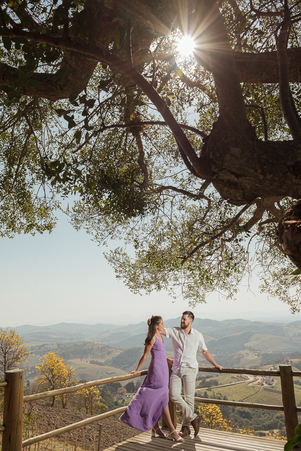 Matthaus e Rebeca sob a luz do sol no Lavandário de Cunha. Ensaio pré-casamento com vista panorâmica da serra e cores vibrantes. Fotografia de casal que captura o romance e a natureza exuberante do interior de SP. Registro profissional e único.
