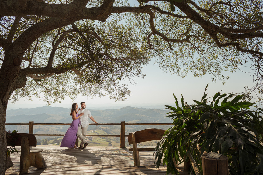Matthaus e Rebeca contemplam a imensidão da Serra da Mantiqueira no deck do Lavandário de Cunha. Fotografia de ensaio pré-casamento que destaca a harmonia entre o casal e a natureza exuberante. Registro profissional, amplo e inspirador.