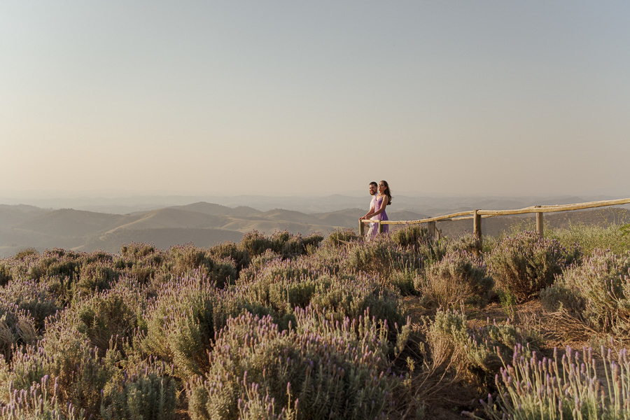 Matthaus e Rebeca contemplam a imensidão no Lavandário de Cunha. Ensaio pré-casamento que destaca os campos de lavanda e o horizonte da serra. Fotografia profissional de noivado com estética romântica e cores suaves.
