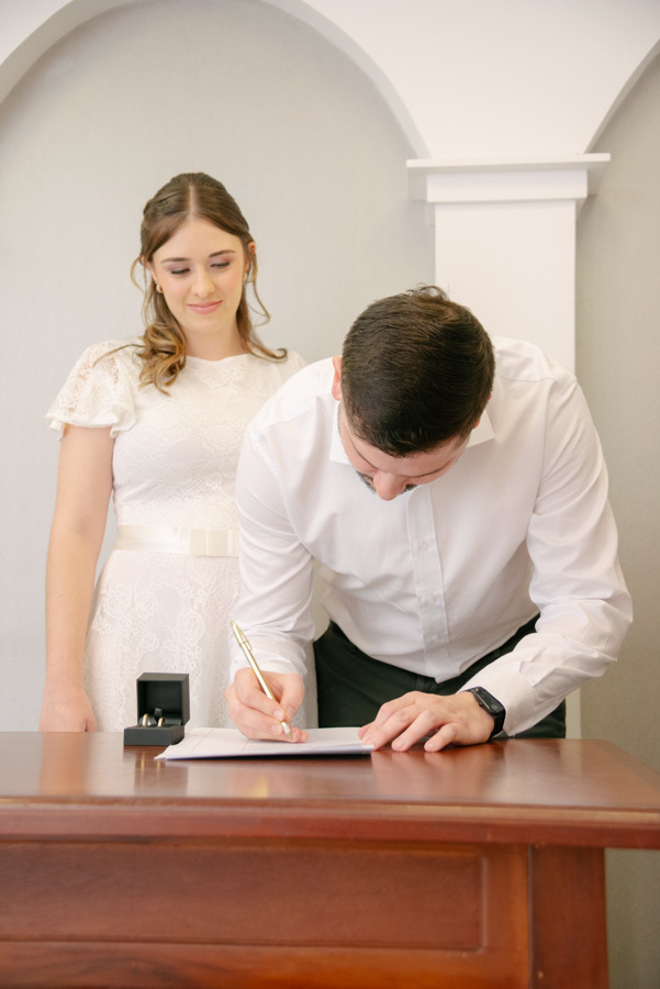 O 'sim' no papel. A fotografia documental captura a importância de cada momento da cerimônia. O registro da assinatura que marca o começo de uma nova história para a família.