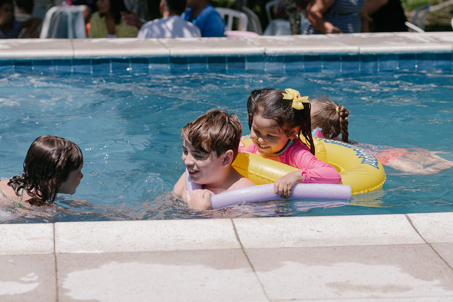 A turma toda reunida para se refrescar! Uma imagem que transmite a energia contagiante de uma 'pool party' infantil. O registro da amizade e da diversão coletiva.