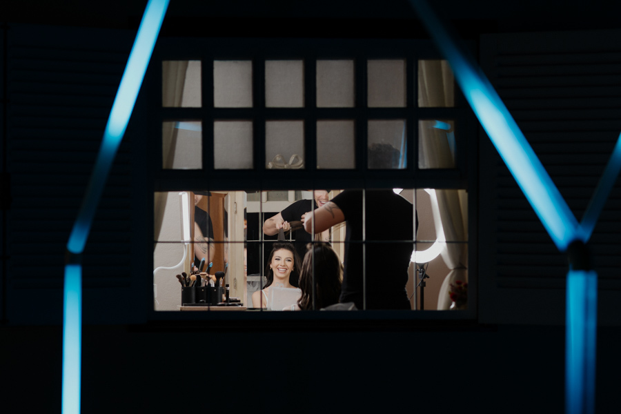 Uma espiadinha mágica nos preparativos. A produção da debutante acontecendo do lado de dentro, vista através da janela, antes da grande celebração em Jacareí - SP.