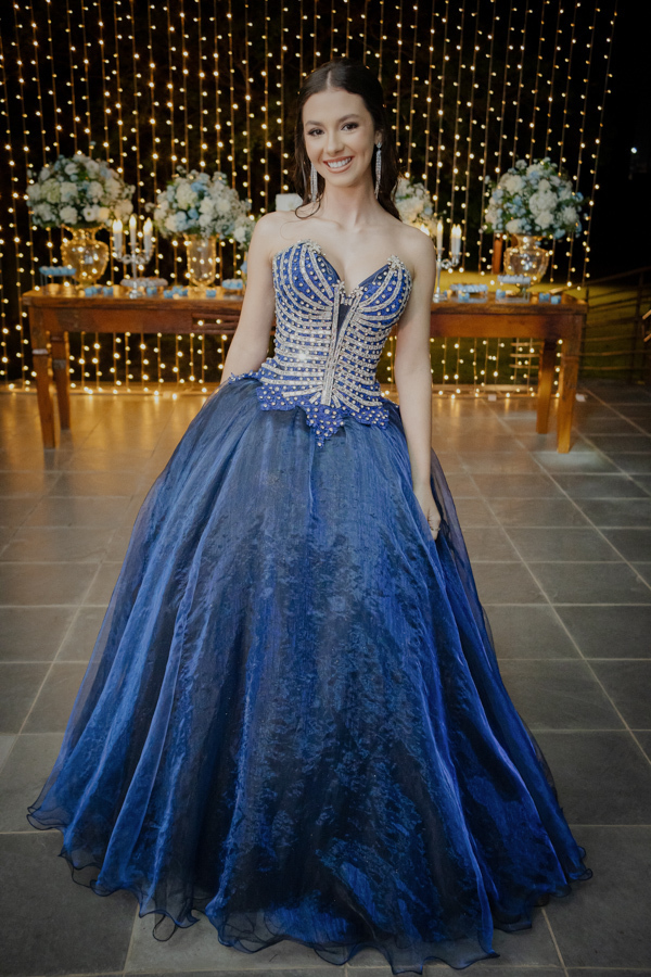 Pronta para a noite da sua vida. A debutante exibe seu vestido azul royal com pedrarias, destacando-se no cenário luxuoso do Buffet Dona Lucy em Jacareí - SP.