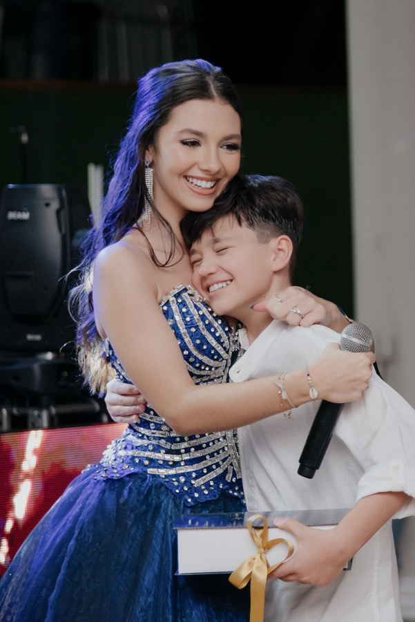 Um abraço que vale mais que mil palavras. A emoção genuína do irmão abraçando a debutante na pista de dança, celebrando juntos esse marco especial de 15 anos.