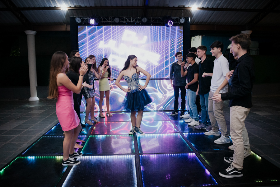 Dança e diversão em família. A debutante, radiante em seu vestido de gala, curte a pista de dança de LED com seu irmão, criando memórias inesquecíveis em Jacareí.