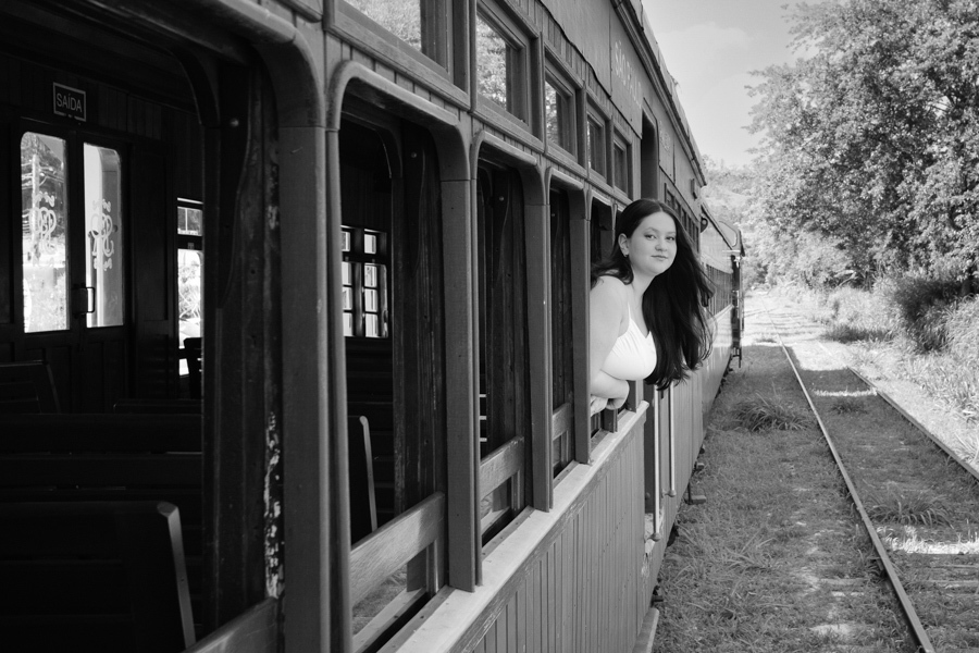 Perspectiva e nostalgia: Foto P&B externa do trem. A composição perfeita dos trilhos e vagões para o book de 15 anos.