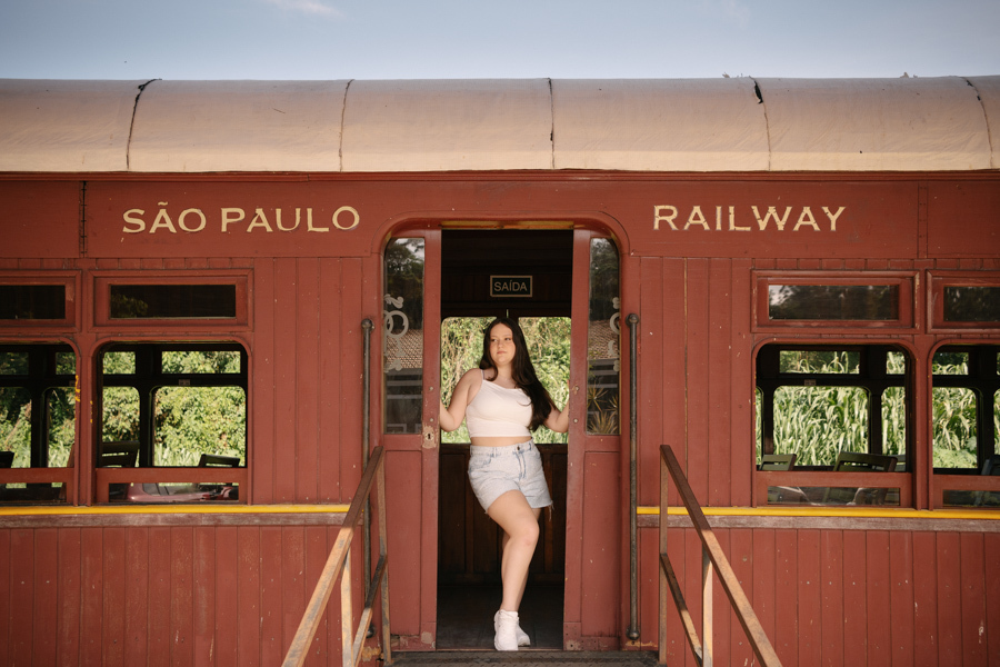 Cenário de cinema: Kiara na plataforma de embarque, sob a placa Railway. O turismo e a história de Guararema compondo o álbum.