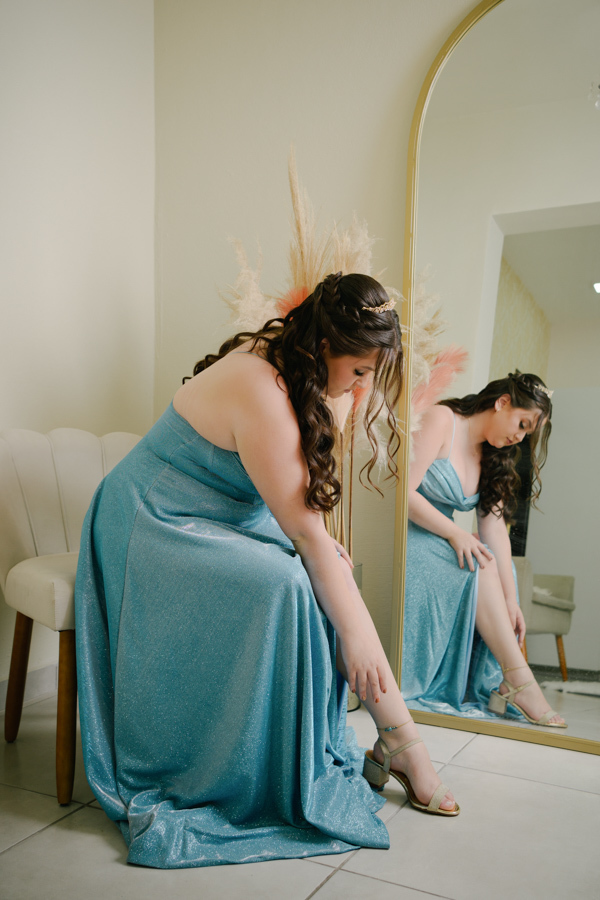 Os últimos retoques! A debutante calça sua sandália, finalizando a produção para a festa. Fotografia de making of de 15 anos em Jacareí, registrando cada detalhe antes de brilhar no Espaço Lisbon.
