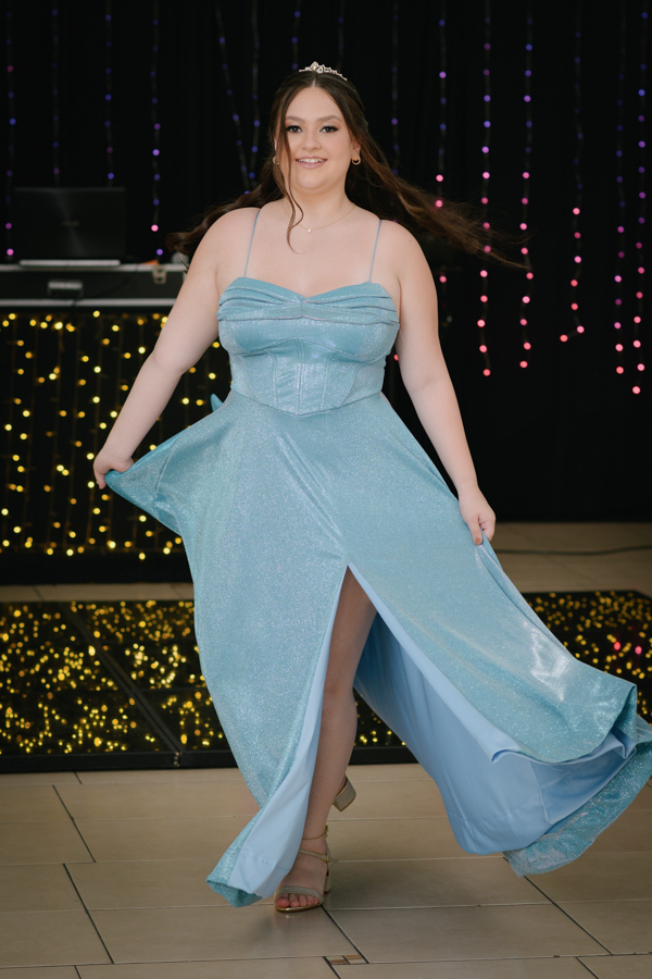 Elegância e postura! Retrato artístico da debutante sentada em frente ao espelho, valorizando o volume e o brilho do vestido azul no making of em Jacareí.