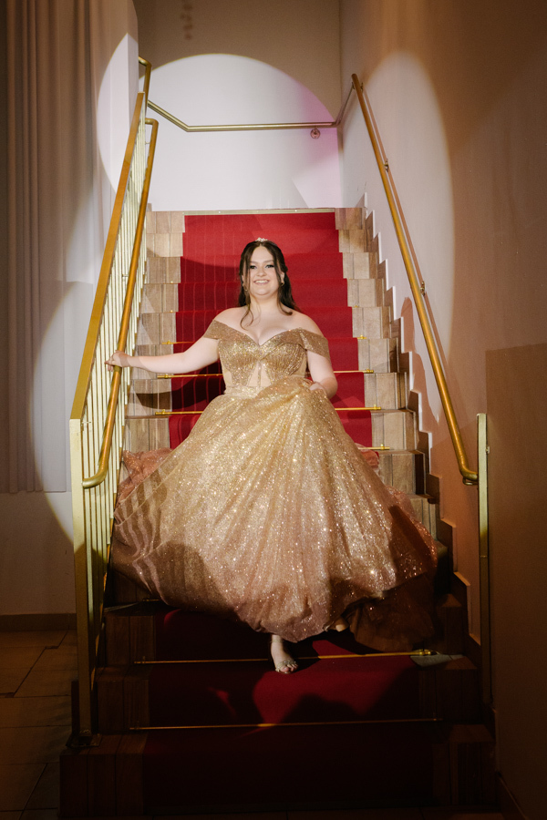 Rainha da noite. A debutante posa majestosamente na escadaria do Espaço Lisbon com seu vestido dourado de 15 anos.