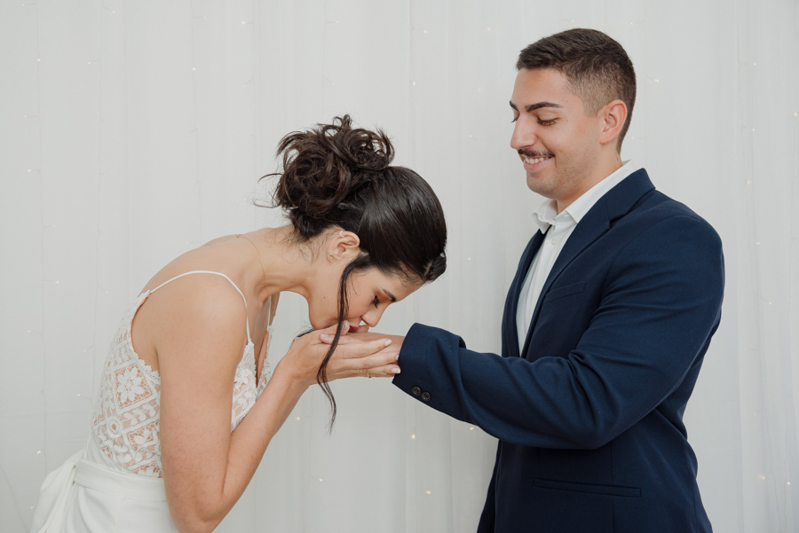 Close de fotógrafo de casamento em Jacareí mostrando a noiva colocando a aliança de ouro no dedo do noivo. Fotografia de detalhes em casamento civil, destacando o simbolismo da união e a delicadeza do momento no Cartório de Jacareí.