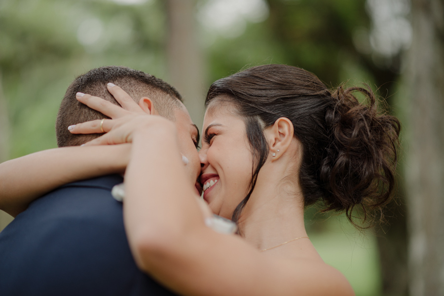 Close do abraço carinhoso entre os noivos Karla e Diego durante ensaio no Parque da Cidade em São José dos Campos. Fotografia de casamento em SJC que destaca a felicidade, o sorriso da noiva e a aliança de casamento em um momento de afeto.