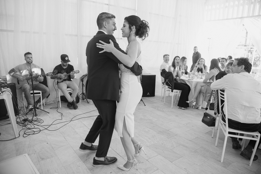 Foto preto e branco dos noivos Karla e Diego dançando durante a recepção. Fotógrafo de casamento em Jacareí registra o momento romântico do casal com banda ao vivo ao fundo, capturando a essência e a alegria da festa após o casamento civil na região.