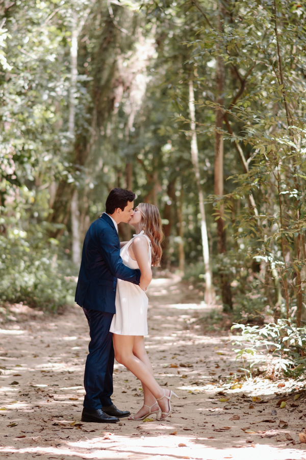 Beijo romântico de Ana Luiza e Felipe Antônio em uma trilha arborizada durante ensaio externo. Fotografia de casamento civil em SJC que captura a paixão e a sintonia do casal em meio à natureza do Parque da Cidade, em São José dos Campos.