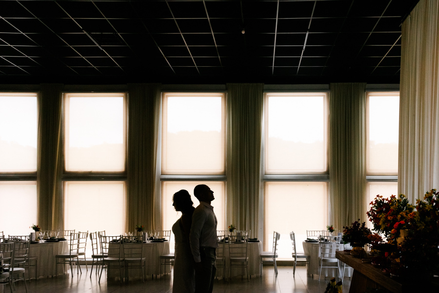 Silhueta da noiva Aline e do noivo Luidgi de costas um para o outro na Chácara Mariah, em Jacareí. Fotografia artística de casamento com luz natural vindo das janelas, destacando o cenário sofisticado e a fotografia profissional em Jacareí.
