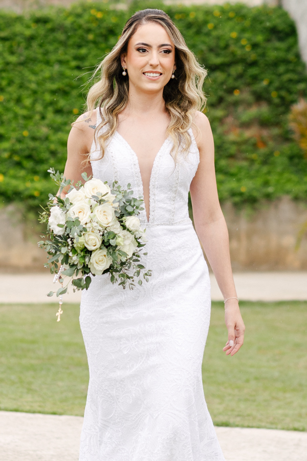Noiva Aline caminhando sorridente em direção ao altar na Chácara Mariah, em Jacareí. Fotografia de casamento destacando o vestido rendado, buquê de rosas brancas e a emoção da cerimônia. Registro profissional por fotógrafo de casamento em Jacareí.