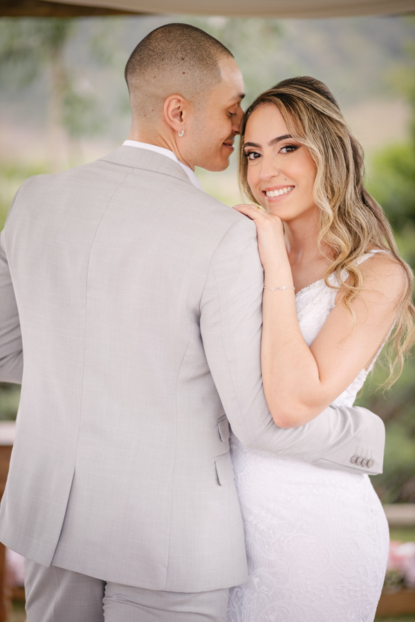 Noiva Aline sorri para a câmera enquanto abraça o noivo Luidgi no altar da Chácara Mariah, em Jacareí. Fotografia de casamento destacando o olhar da noiva e a cumplicidade do casal. Registro profissional realizado por fotógrafo de casamento em Jacareí.