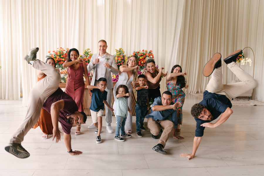 Noivos Aline e Luidgi posando com convidados e crianças em momento divertido na recepção na Chácara Mariah. Fotografia de casamento em Jacareí capturando a animação da festa com convidados fazendo poses. Registro profissional por fotógrafo em Jacareí.