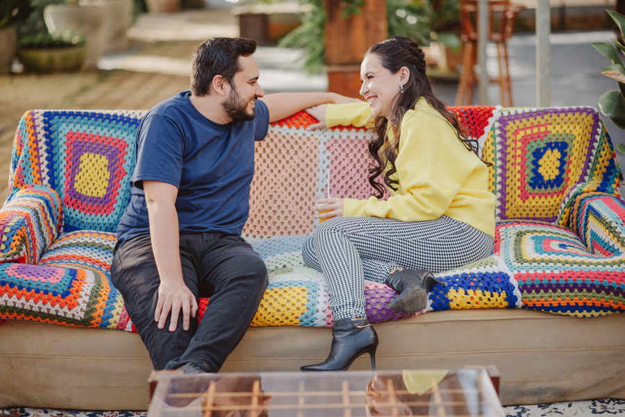 Sorrisos e cores no pré-wedding de André e Nathália em Campos do Jordão. Registro lifestyle em sofá de crochê, destacando a conexão e alegria do casal na Serra da Mantiqueira. Fotógrafo de casamento em SP especializado em ensaios externos e espontâneos.
