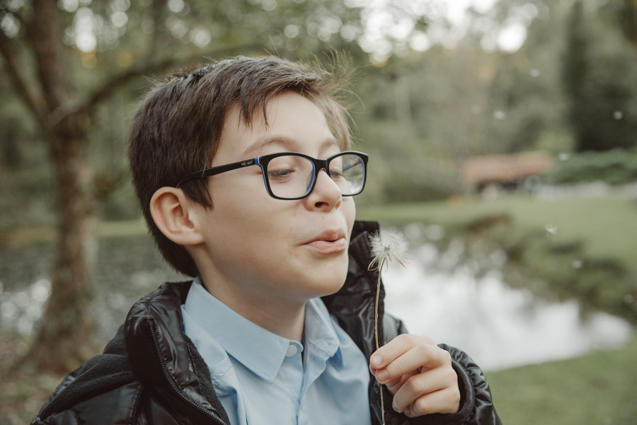 Momento de pureza e leveza: filho de André e Nathália soprando um dente-de-leão. Ensaio pré-wedding com família em Campos do Jordão. Fotógrafo na Serra da Mantiqueira capturando a espontaneidade e os pequenos detalhes que emocionam.