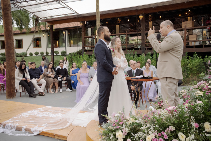 Noiva Claudia e noivo Matheus atentos às palavras do celebrante no altar circular do Boulevard Jacareí. Fotografia de casamento em plano médio destacando a cerimônia ao ar livre e a emoção dos convidados ao fundo, por Gilson Dias.