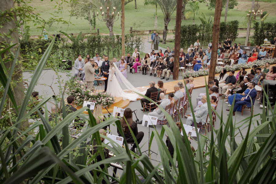 Vista aérea da cerimônia de Claudia e Matheus no Boulevard Jacareí, capturando os noivos no altar, convidados e músicos entre a vegetação. Fotografia de casamento que destaca a harmonia do evento ao ar livre, registrada por Gilson Dias.