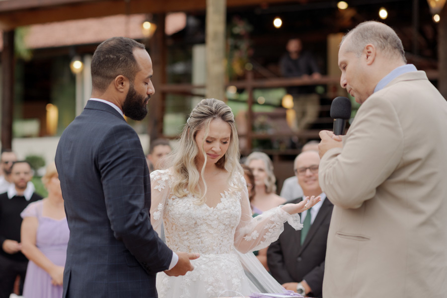 Noiva Claudia chora emocionada durante a oração final no altar do Boulevard Jacareí. Fotografia de casamento capturando a profunda sensibilidade e espiritualidade do casal Matheus e Claudia ao ar livre, registrada por Gilson Dias.