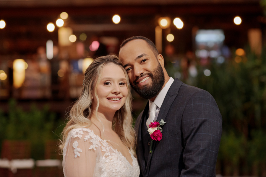 Retrato sorridente dos noivos Claudia e Matheus no Boulevard Jacareí após a cerimônia. Close do casal com rostos próximos e luzes decorativas ao fundo, capturando a felicidade do casamento em fotografia de Gilson Dias.