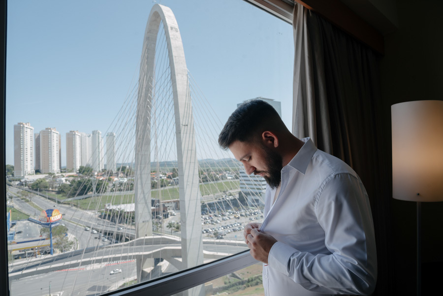Noivo se prepara para o casamento em hotel com vista para a Ponte Estaiada de São José dos Campos. Registro do making of do noivo com luz natural e estilo editorial, capturado pelo fotógrafo de casamentos Gilson Dias no Vale do Paraíba.