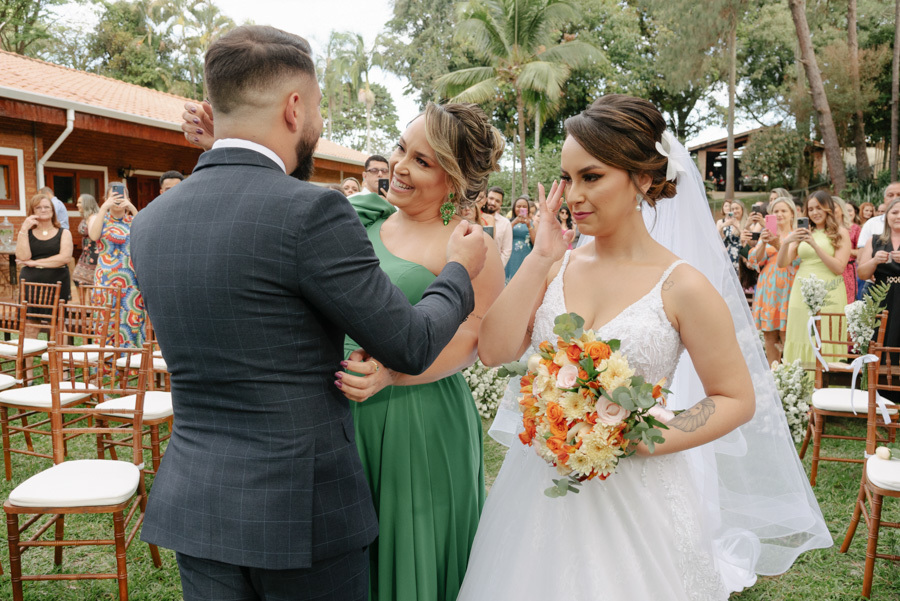 Noivo Diego recebe a noiva Thayná e sua mãe no altar em Taubaté. Momento de emoção com a noiva enxugando lágrimas no Espaço Verde Vale, registrado com estilo natural e espontâneo pelo fotógrafo Gilson Dias no Vale do Paraíba.