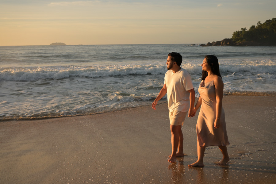 Isabela e Isaac caminham de mãos dadas pela beira do mar na Praia do Félix, Ubatuba, sob a luz suave da manhã. Fotografia profissional de pré-wedding capturando a leveza do casal em meio às ondas e à natureza exuberante do litoral norte.