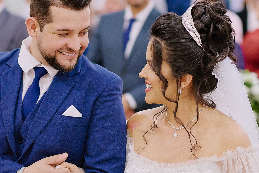 Close dos noivos Cassiano e Paloma trocando olhares apaixonados no altar da Capela Nossa Senhora Aparecida, em São José dos Campos. Fotografia documental realçando a conexão e a felicidade do casal durante a cerimônia religiosa.