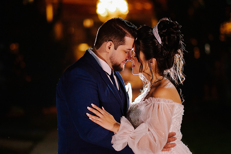 Retrato artístico dos noivos Paloma e Cassiano em um momento de carinho, com as testas encostadas e luz de contorno destacando a silhueta em São José dos Campos. Fotografia noturna de casamento com atmosfera romântica e sofisticada após a cerimônia.