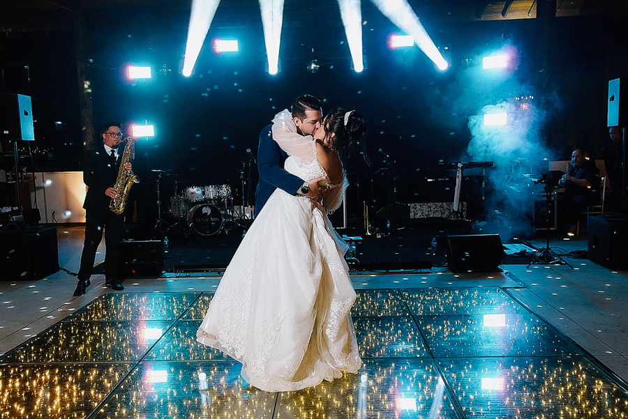 Noivos Paloma e Cassiano dançam e se beijam na pista de LED durante a festa de casamento em São José dos Campos. A fotografia destaca a iluminação cênica, o saxofonista ao fundo e a celebração vibrante na Chácara Parque dos Príncipes.