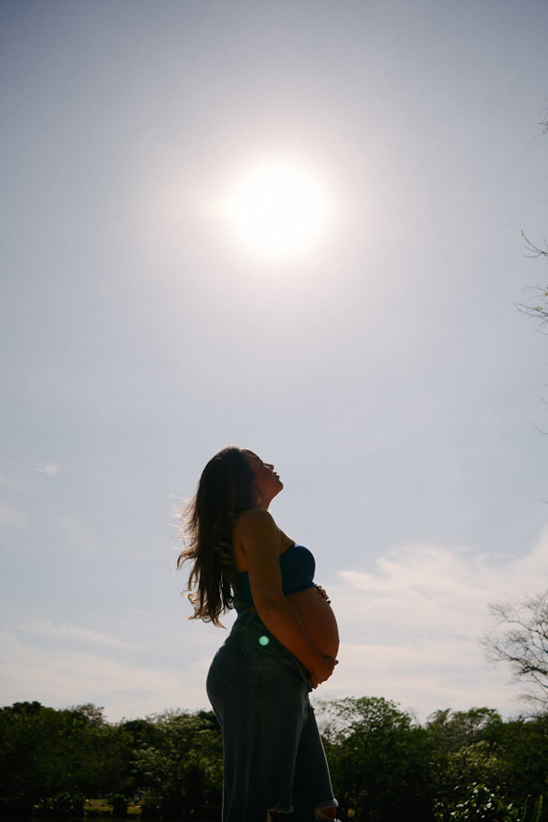 Fotografia de gestante em São José dos Campos. Silhueta de Lorrana sob o sol forte no Parque da Cidade, destacando a barriga à espera de Pedro. Uma composição artística ao ar livre que celebra a força e a iluminação única da maternidade.