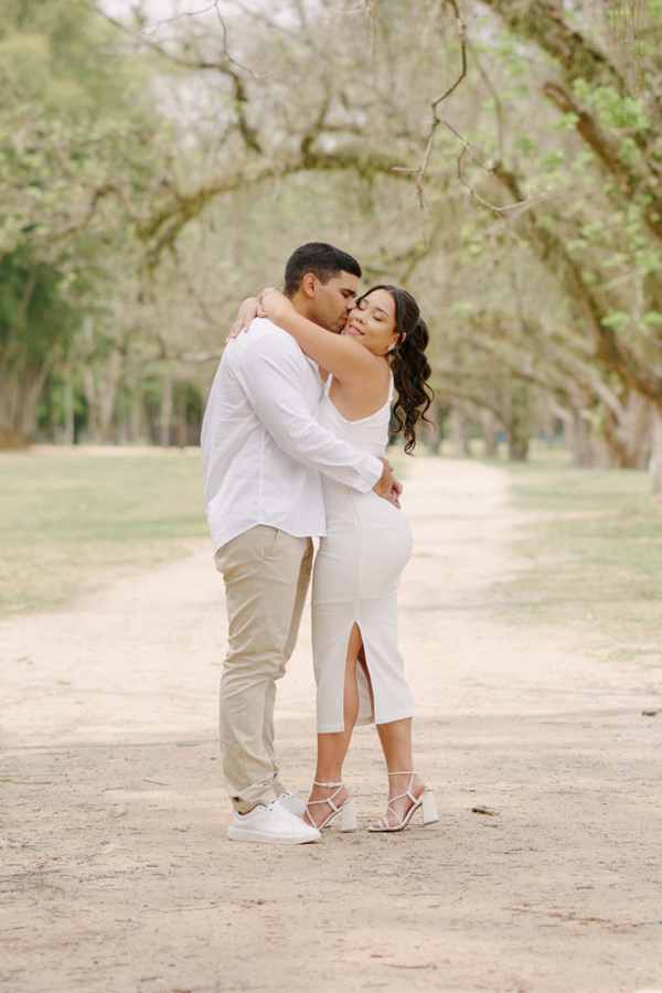 Fotografia de casamento em SJC: Luiz Carlos beija o rosto de Gabrielle em um abraço afetuoso. O ensaio no Parque da Cidade em São José dos Campos destaca a leveza e a felicidade do casal após o casamento civil, em meio à natureza.