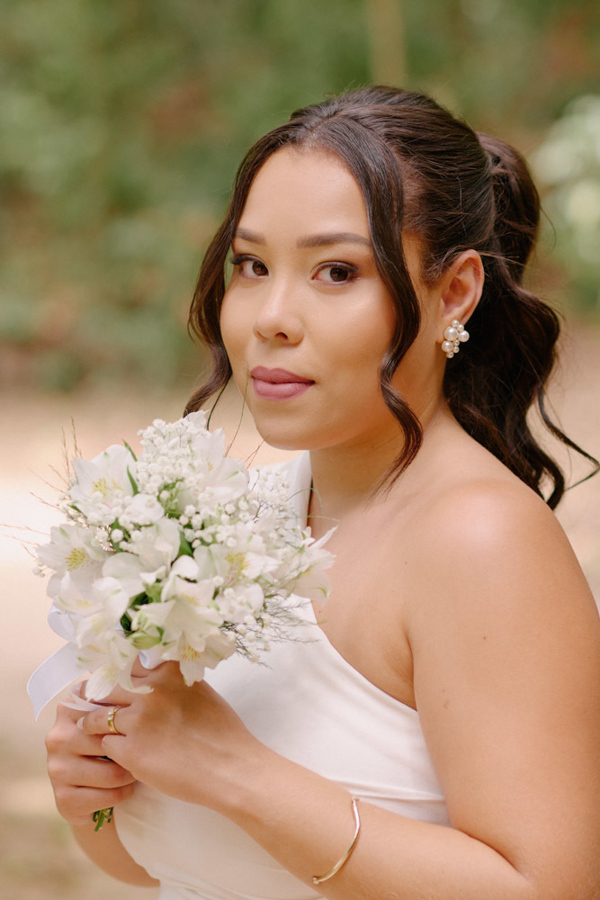 Fotografia de casamento em SJC: Retrato da noiva Gabrielle no Parque da Cidade, segurando seu buquê de flores brancas. O registro destaca sua elegância e serenidade durante o ensaio pós-civil em São José dos Campos.