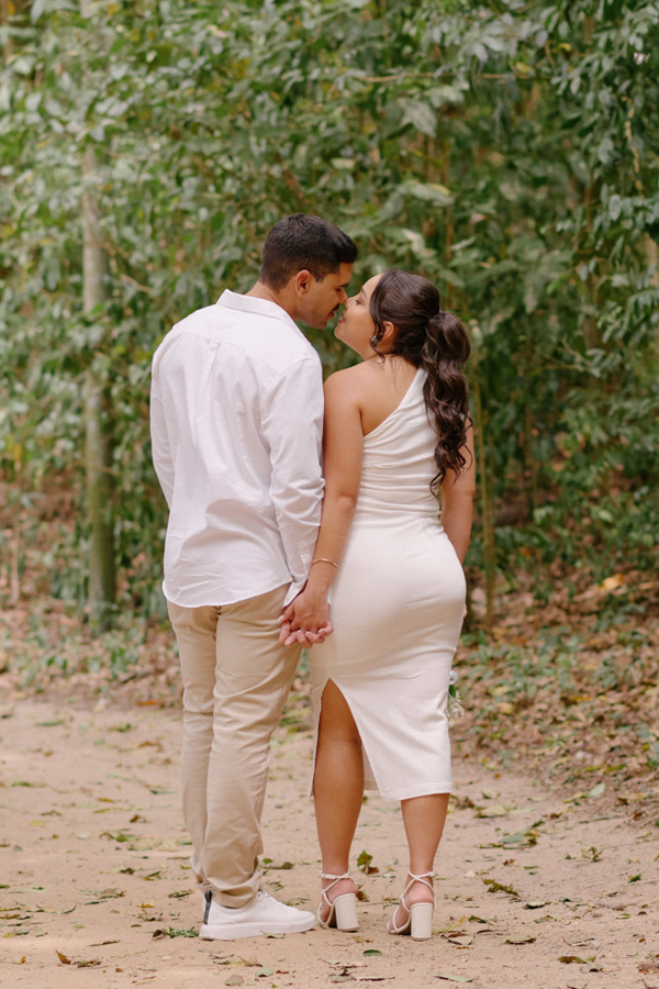Fotografia de casamento em SJC: Gabrielle e Luiz Carlos de costas, de mãos dadas, em momento romântico no Parque da Cidade. O registro destaca a silhueta do casal e a conexão afetiva durante o ensaio pós-civil em São José dos Campos.