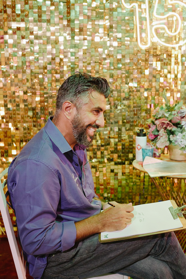 Um caricaturista sorri enquanto produz desenhos ao vivo na festa de 15 anos da Anna Clara. O registro documental em Jacareí destaca o clima artístico da celebração, onde a arte e a criatividade foram protagonistas em cada detalhe do evento.